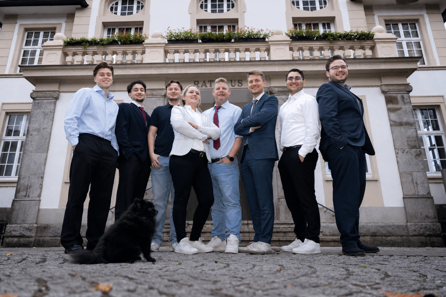 Team der Primus Finanzdienst GmbH vor dem Hennefer Rathaus mit Blick in die Kamera als Symbol für persönliche Beratung und Kundennähe.